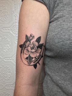 a woman with a black and white tattoo on her arm, holding a small flower