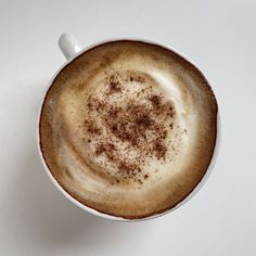 a cappuccino in a white cup with cinnamon sprinkles