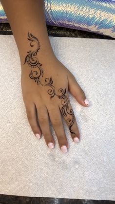 a woman's hand with a henna tattoo on her left arm and foot