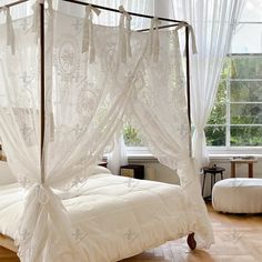 a canopy bed with white curtains in a bedroom