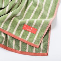 a green and white striped towel laying on top of a table next to a red tag