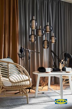 two chairs and a table in front of a curtained wall with lights on it