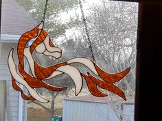 a stained glass window with an orange and white bird hanging from it's side