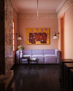 a living room filled with furniture and a painting hanging on the wall above it's windows