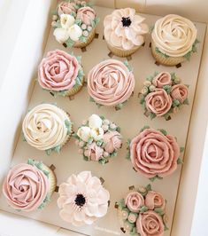 cupcakes decorated with pink and white flowers in a box