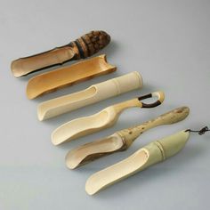 five different types of wooden utensils lined up in a row on a gray surface