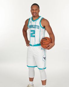 a man holding a basketball while standing in front of a white background with the words charlotte written on it