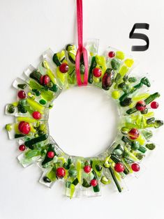 a wreath made out of gummy bears and candy canes hanging from a red ribbon