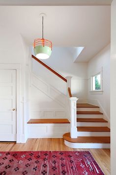 an empty room with stairs and rug on the floor