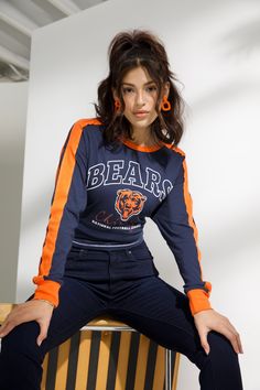 a young woman sitting on top of a chair wearing an orange and blue shirt with bears on it