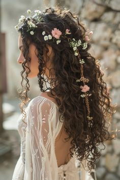 a woman with long curly hair wearing a white dress and flowers in her hair is looking off into the distance