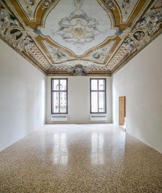 an empty room with two windows and a ceiling painted in gold, white and blue