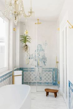 a bathroom with blue and white tile, chandelier, bathtub and shower