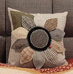 a close up of a pillow on a bed with a decorative flower design in the middle