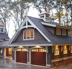 a two car garage with lights on the windows and an attached dormer above it