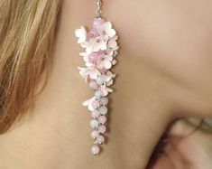 a close up of a woman's ear wearing pink and white flowers on it