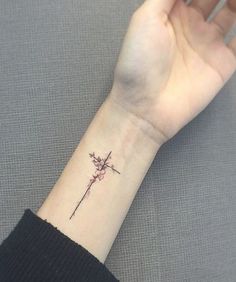 a woman's wrist with a small flower tattoo on the left side of her arm