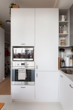 a kitchen with white cupboards and stainless steel appliances in the middle of the room