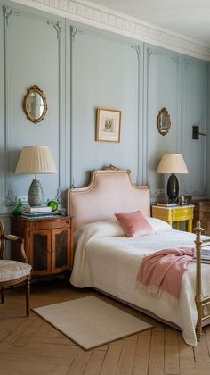 a bedroom with blue walls and wooden flooring, two lamps on either side of the bed