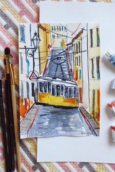 a drawing of a yellow train on the tracks next to some watercolor pencils