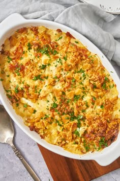 a casserole dish with meat, cheese and parsley in it on a wooden cutting board