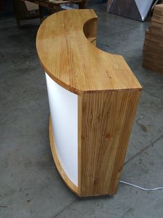 a curved wooden counter with white paint on the top and bottom, in a warehouse