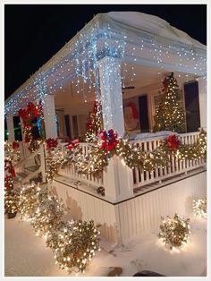 a house covered in christmas lights and garlands with red bows on the front porch