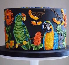 there is a cake decorated with parrots and flowers on the top of a table