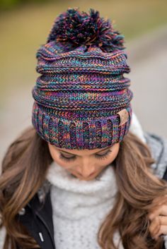 a woman with long hair wearing a multicolored knitted beanie and scarf