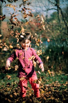 a little boy standing in the leaves with his arms out