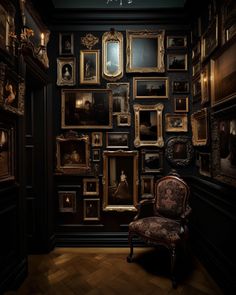 a chair sitting in front of a wall full of framed pictures on it's walls