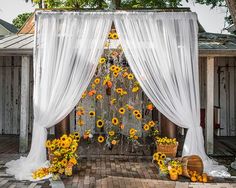 an outdoor wedding ceremony with sunflowers and white drapes on the door way