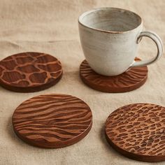 four wooden coasters with designs on them and a coffee cup in the middle one