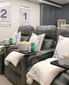 two recliners with popcorn and drinks on them in a home theater room setting