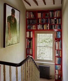 the bookshelves are full of books and there is a painting on the wall