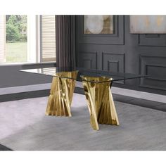 a glass table with two gold pedestals on it in front of a large window