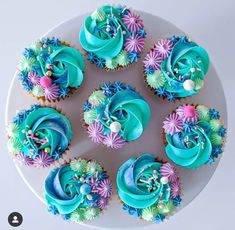 cupcakes with blue frosting and colorful decorations on a plate