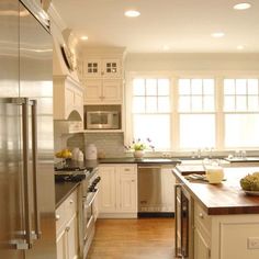 a clean kitchen with stainless steel appliances and wood flooring, along with white cabinets