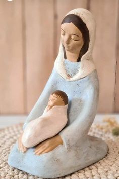 a ceramic figurine of a woman holding a baby in her arms, on a rug