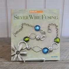 silver wire fishing bracelet with blue, green and white glass bead charms on it