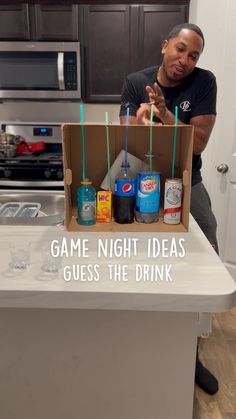 a man sitting on top of a kitchen counter next to an open box filled with drinks