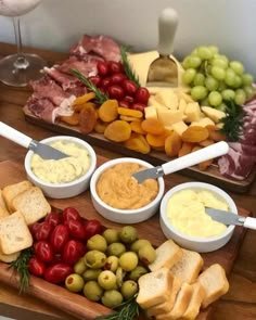 an assortment of cheeses, crackers and olives on a wooden platter