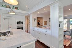 a kitchen with white cabinets and an island in the middle is seen from across the room