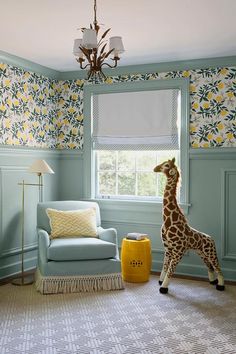 a giraffe standing next to a window in a living room with blue walls