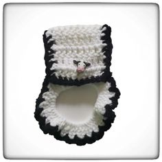 a crocheted panda bear is hanging from the side of a white and black object