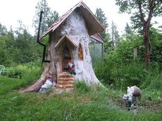 a tree stump house in the middle of a grassy area with stairs leading up to it