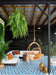 an outdoor living area with blue and white tiles on the floor, potted plants and hanging chairs