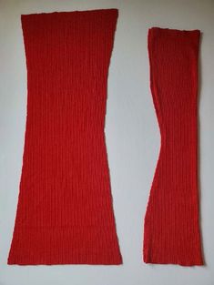 two pieces of red knitted material on a white surface with one piece cut out