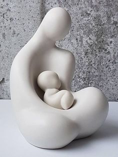 a white sculpture sitting on top of a table next to a gray wall and floor