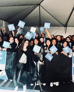 a group of people holding up signs under a tent